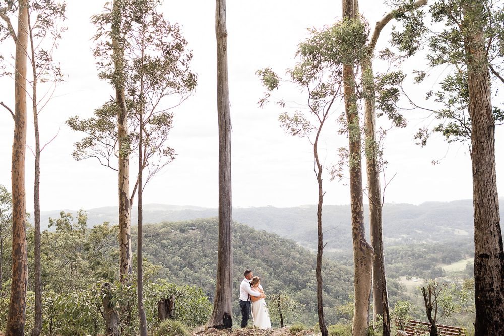A couple framed between tall trunks, the valley beyond