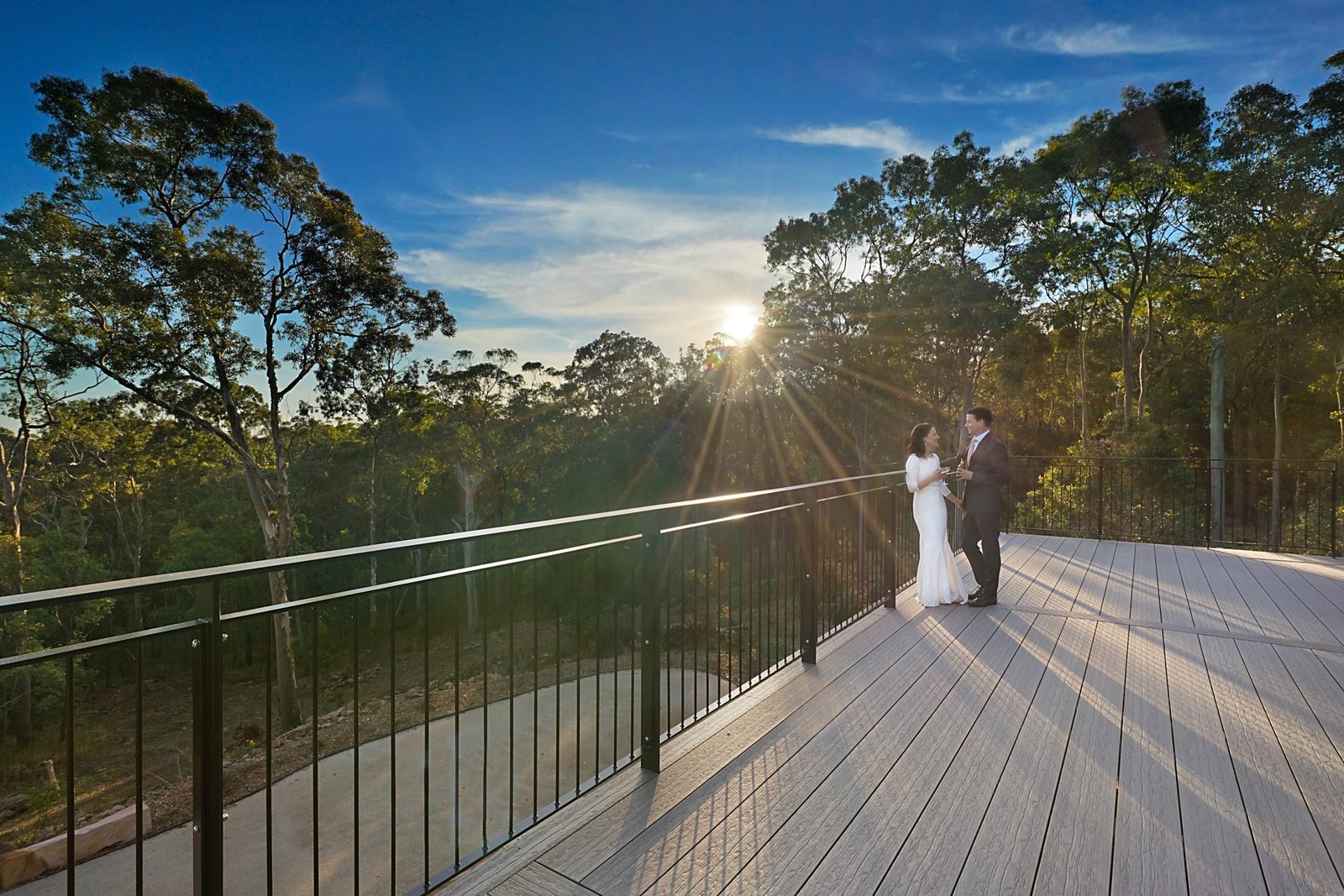 A couple on the timber deck at sunset with the valley below