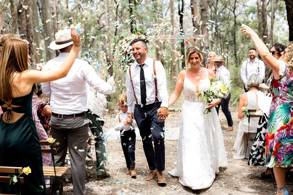 A couple walking back up the aisle to cheering guests