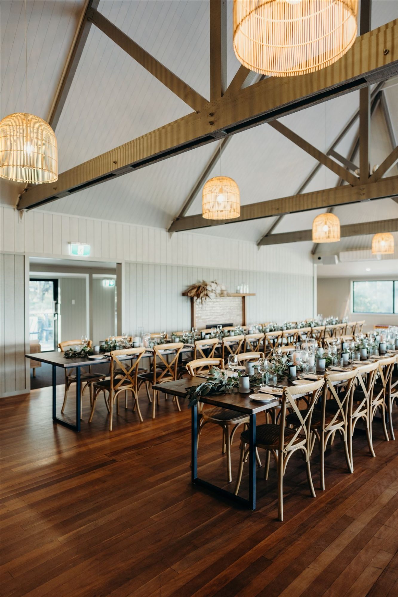 The reception room: white vaulted ceiling, rattan pendants and long tables